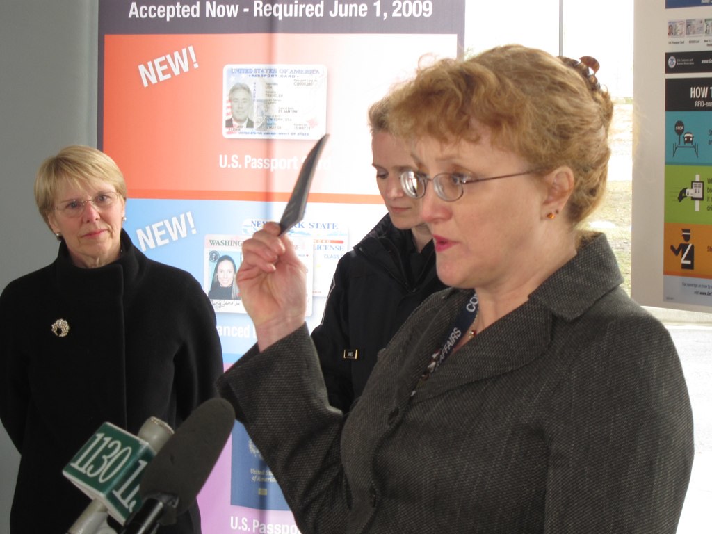 Official displaying a new passport card design, tied to the October 2026 visa bulletin wait